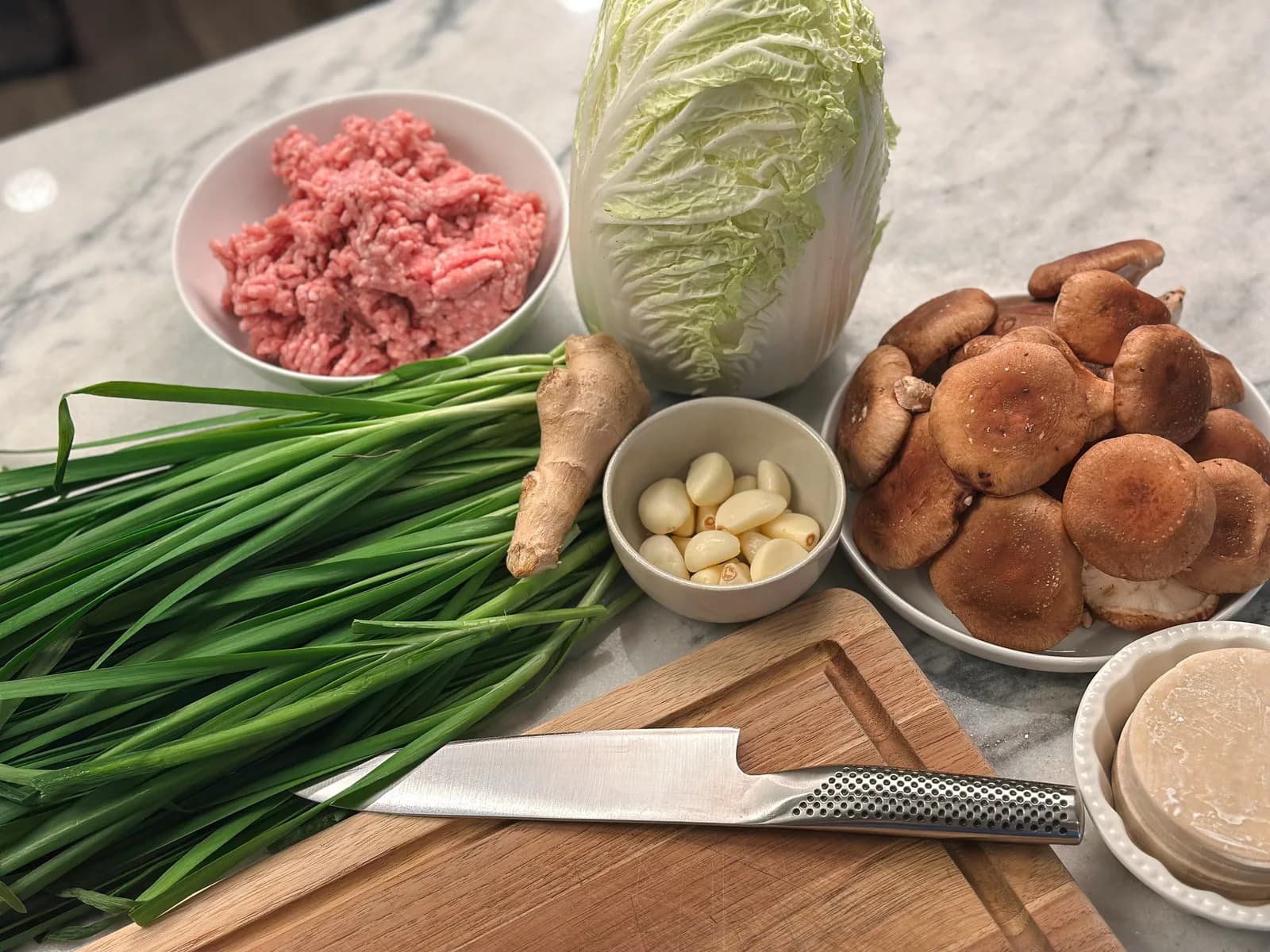 Potsticker filling and wrappers laid out on a surface, ready to fold